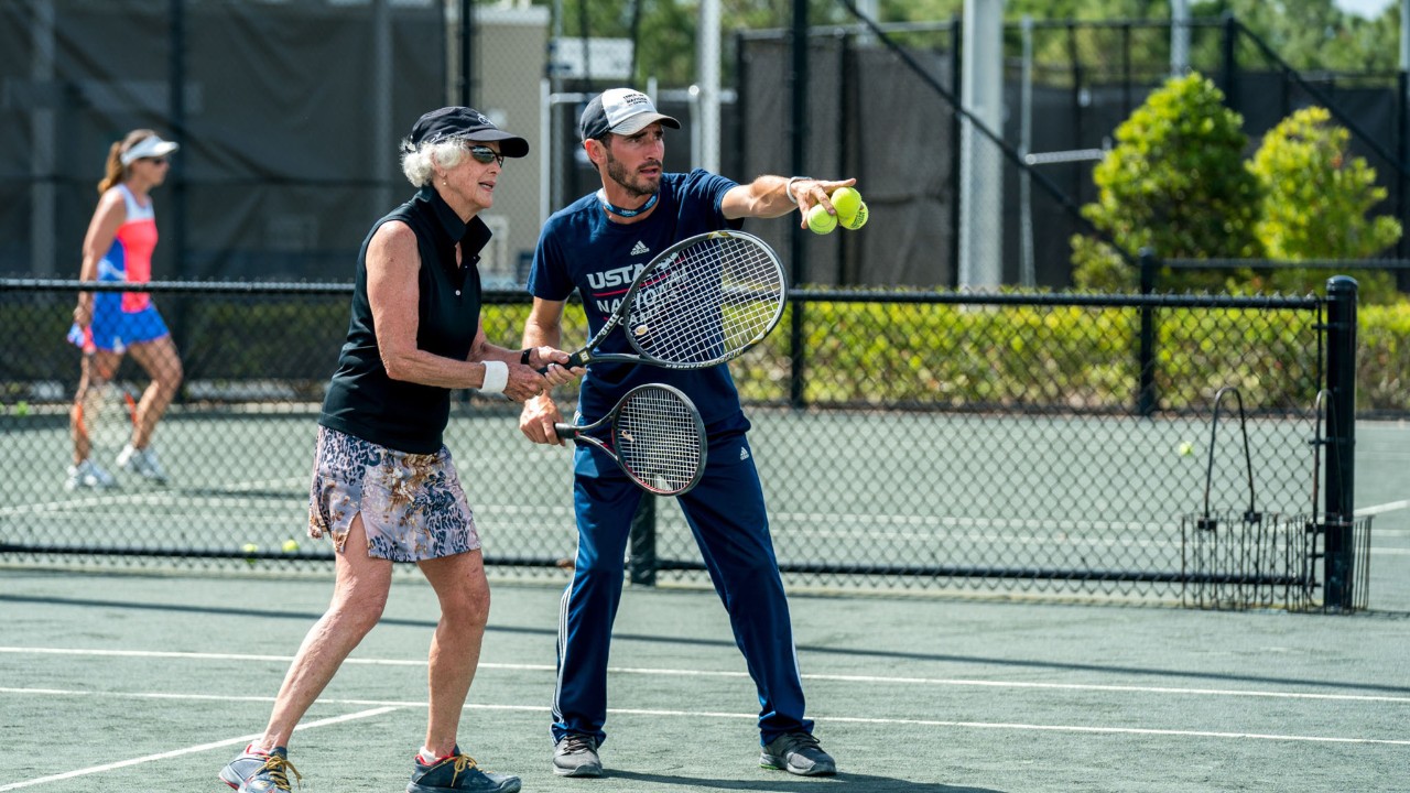 A man and a woman celebrating a win on a tennis court at the USTA National Campus.