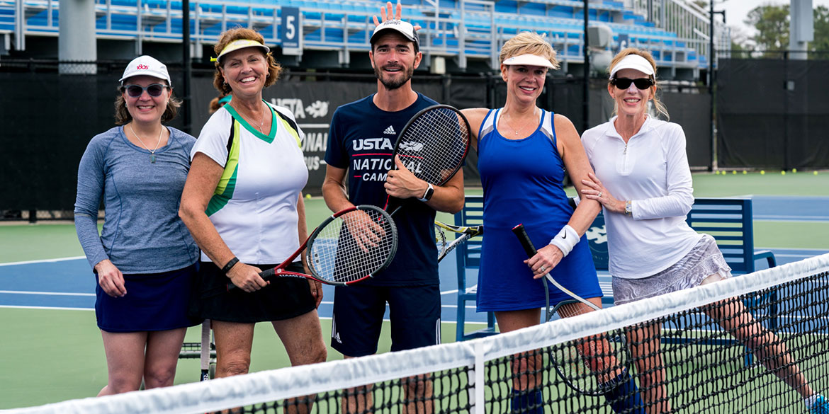 A man and a woman celebrating a win on a tennis court at the USTA National Campus.