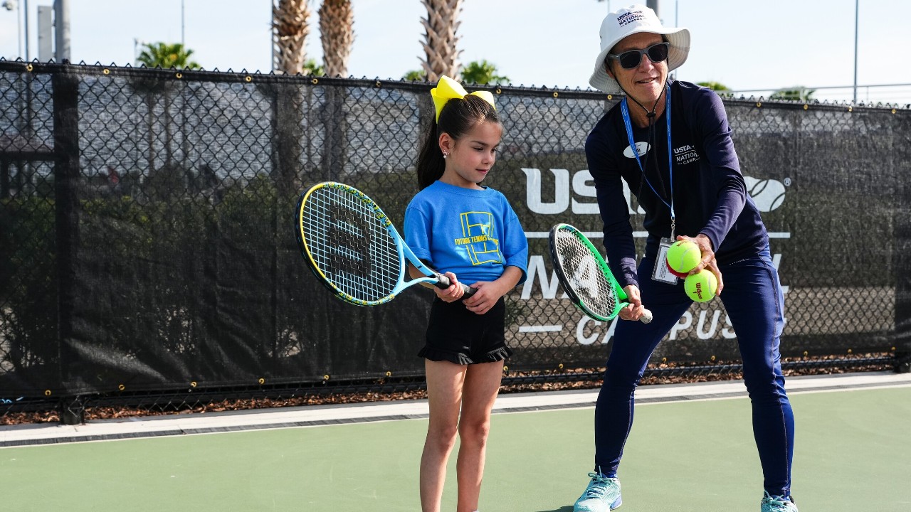 A man and a woman celebrating a win on a tennis court at the USTA National Campus.